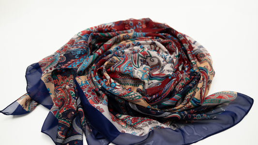 cotton voile shawl featuring intricate designs with red, orange, white, and blue tones. rolled.