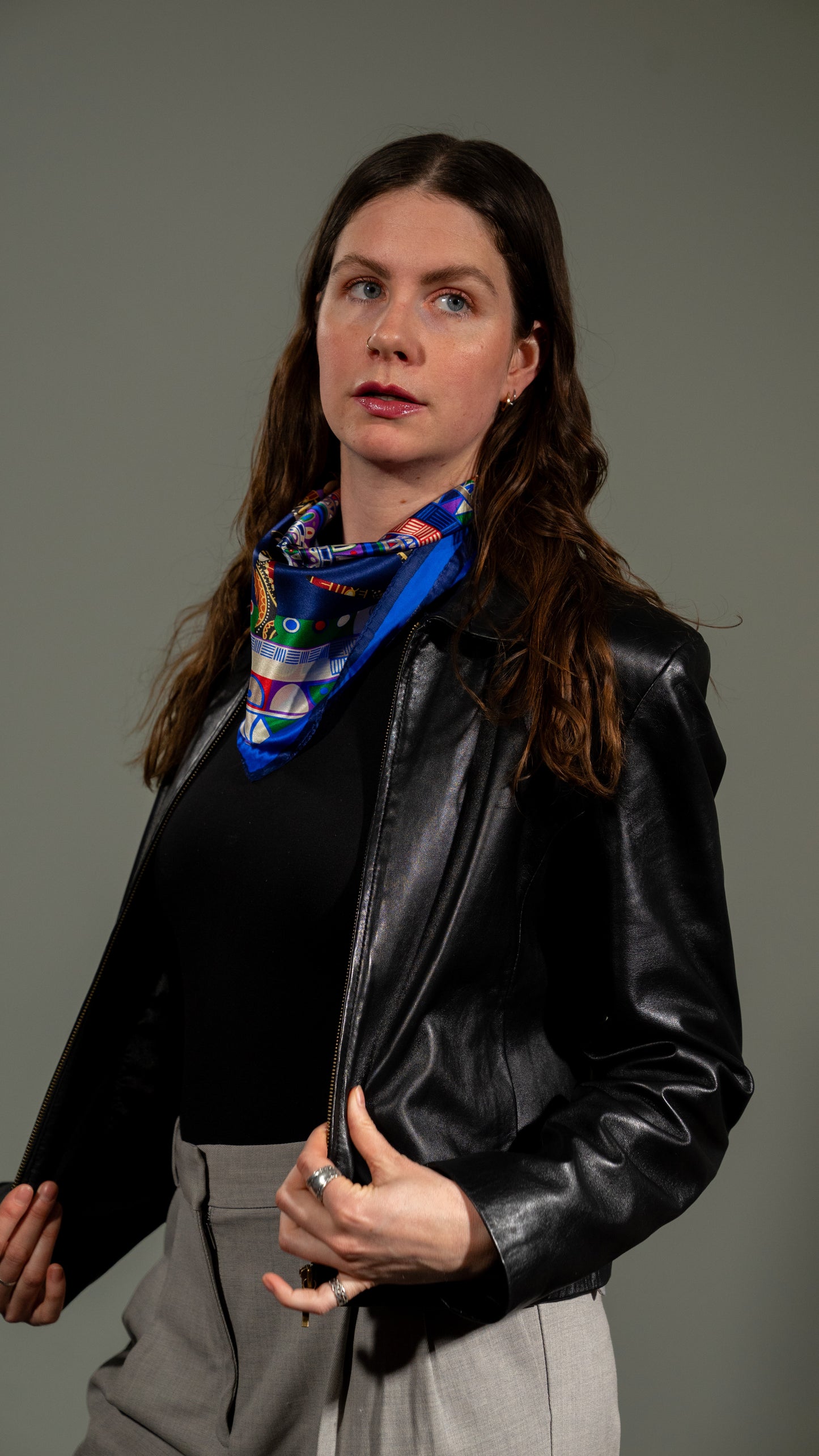 female model in a black leather jacket wearing a colourful square silk scarf, 100% pure silk with mandala design and predominantly blue tones, looking off camera