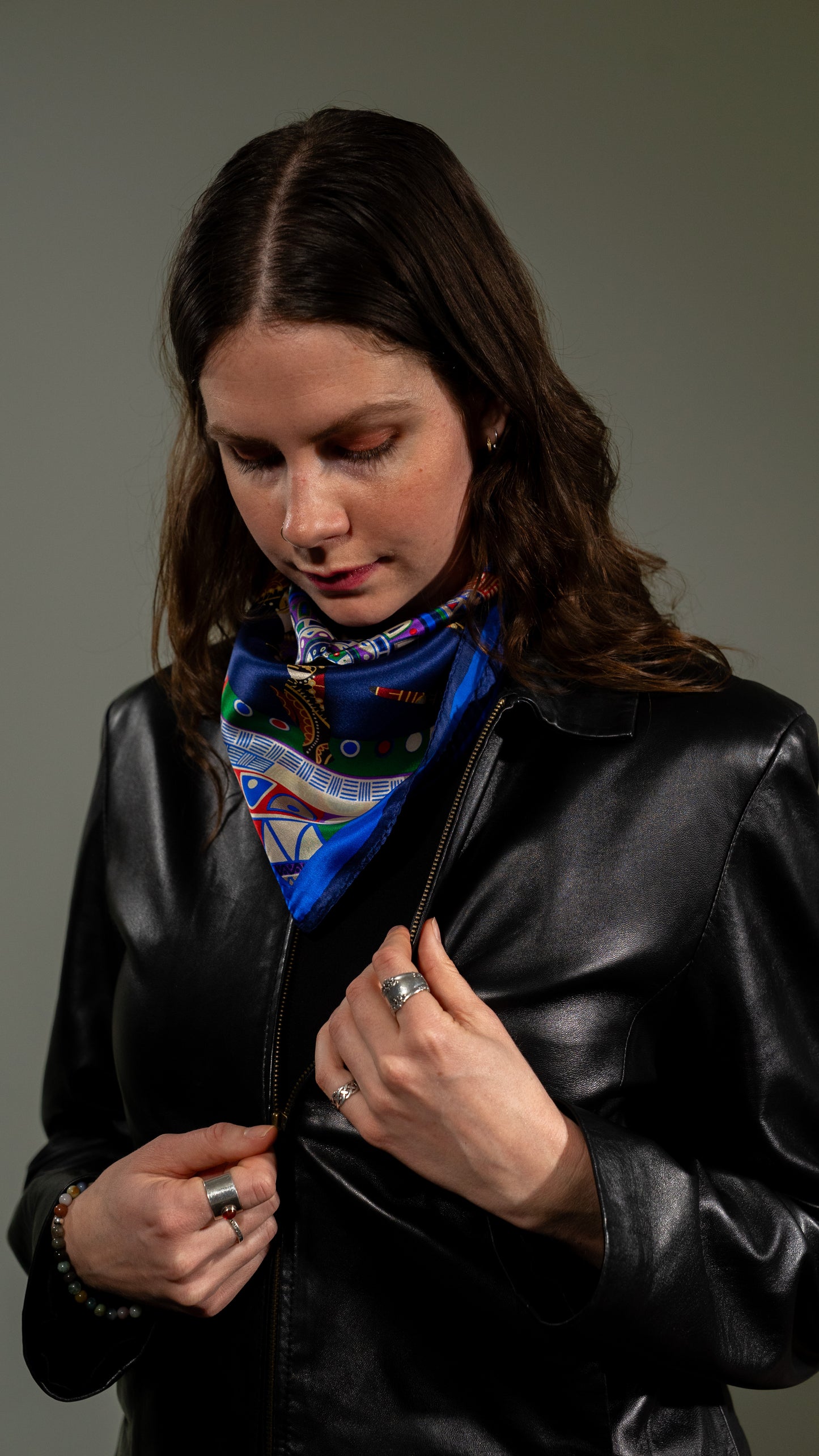 model unzipping leather jacket and wearing a Colourful square silk scarf, 100% pure silk, mandala design with predominantly blue tones