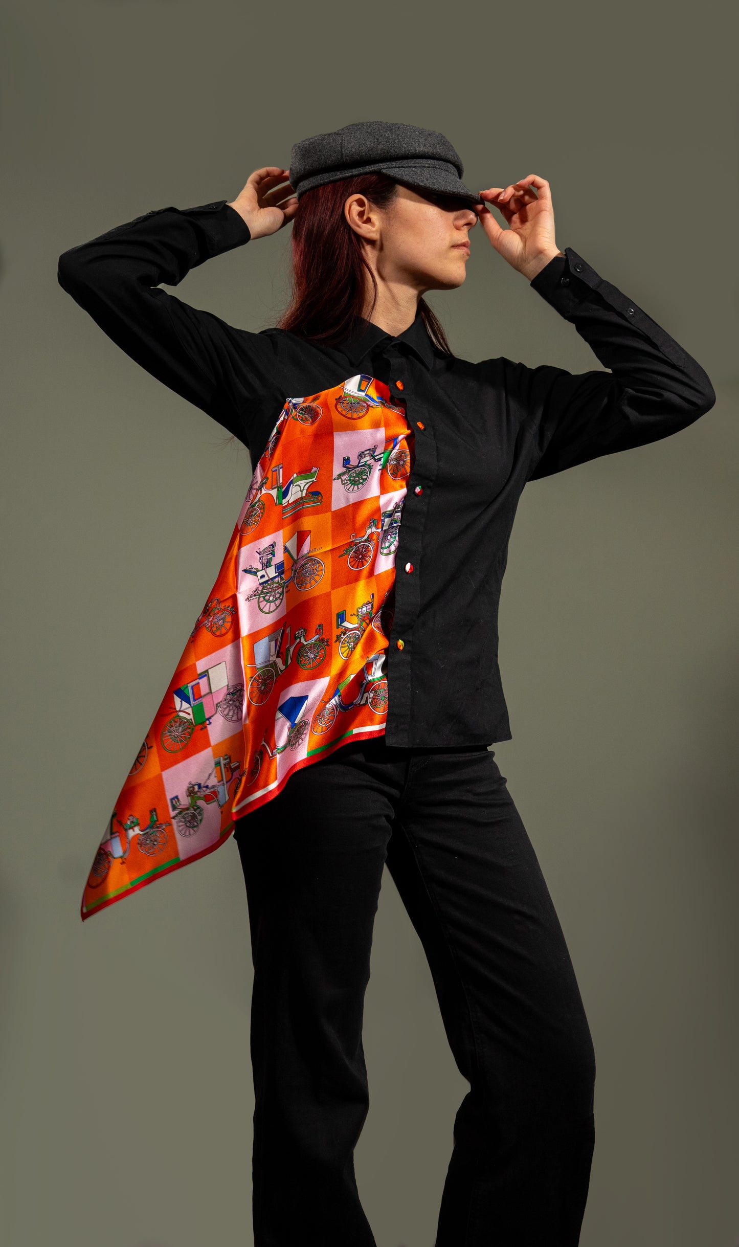 model wearing a colourful square silk scarf, 100% pure silk, design with victorian vehicles and predominantly orange tones, styled into a button-up shirt