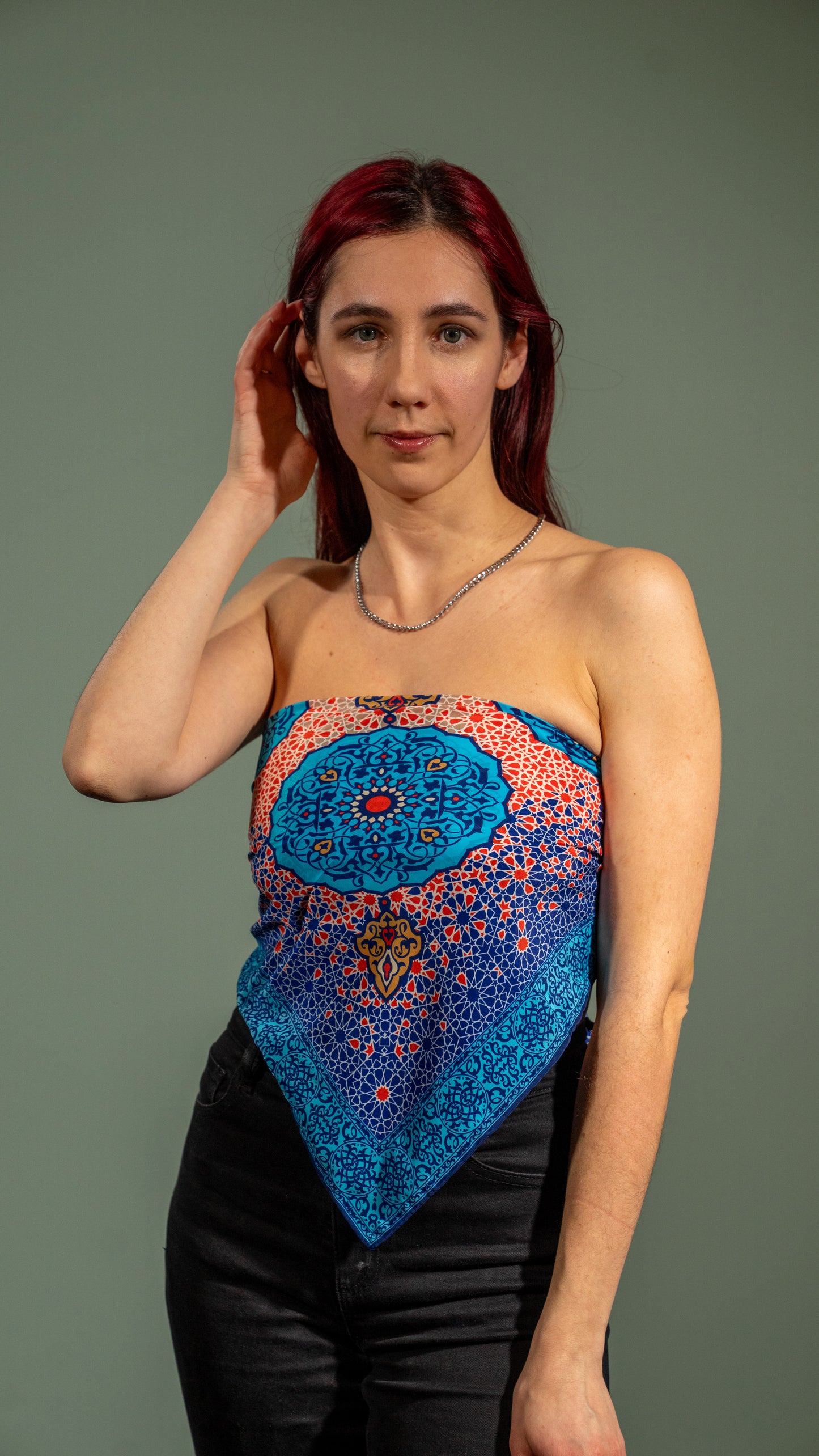 female model wearing a vegan silk scarf with light and dark blue, yellow, orange, and white tones, featuring intricate designs, styled as a beach top