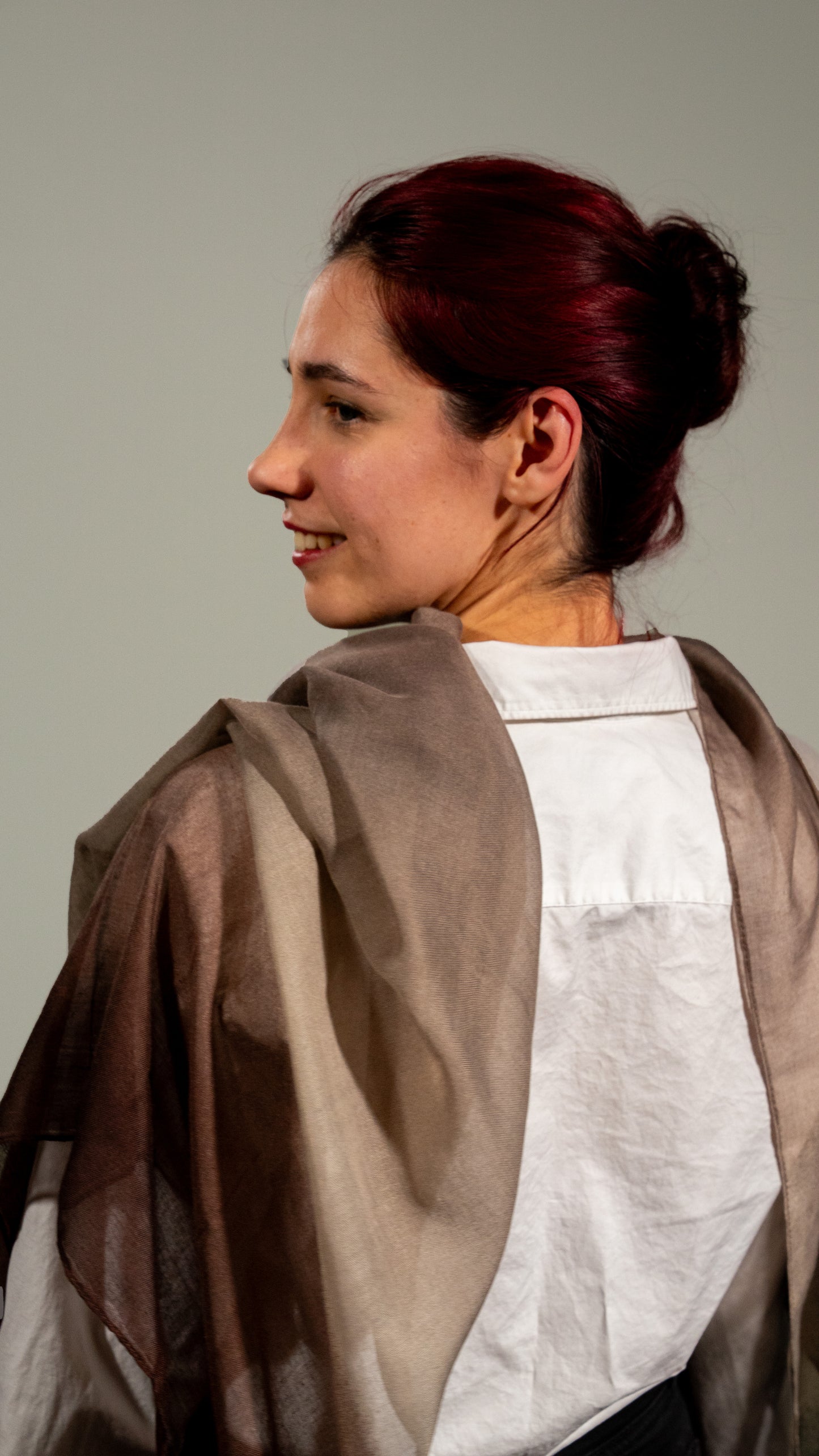female model shot from the back: wearing wool silk shawl with earthly tones of light and dark brown and black