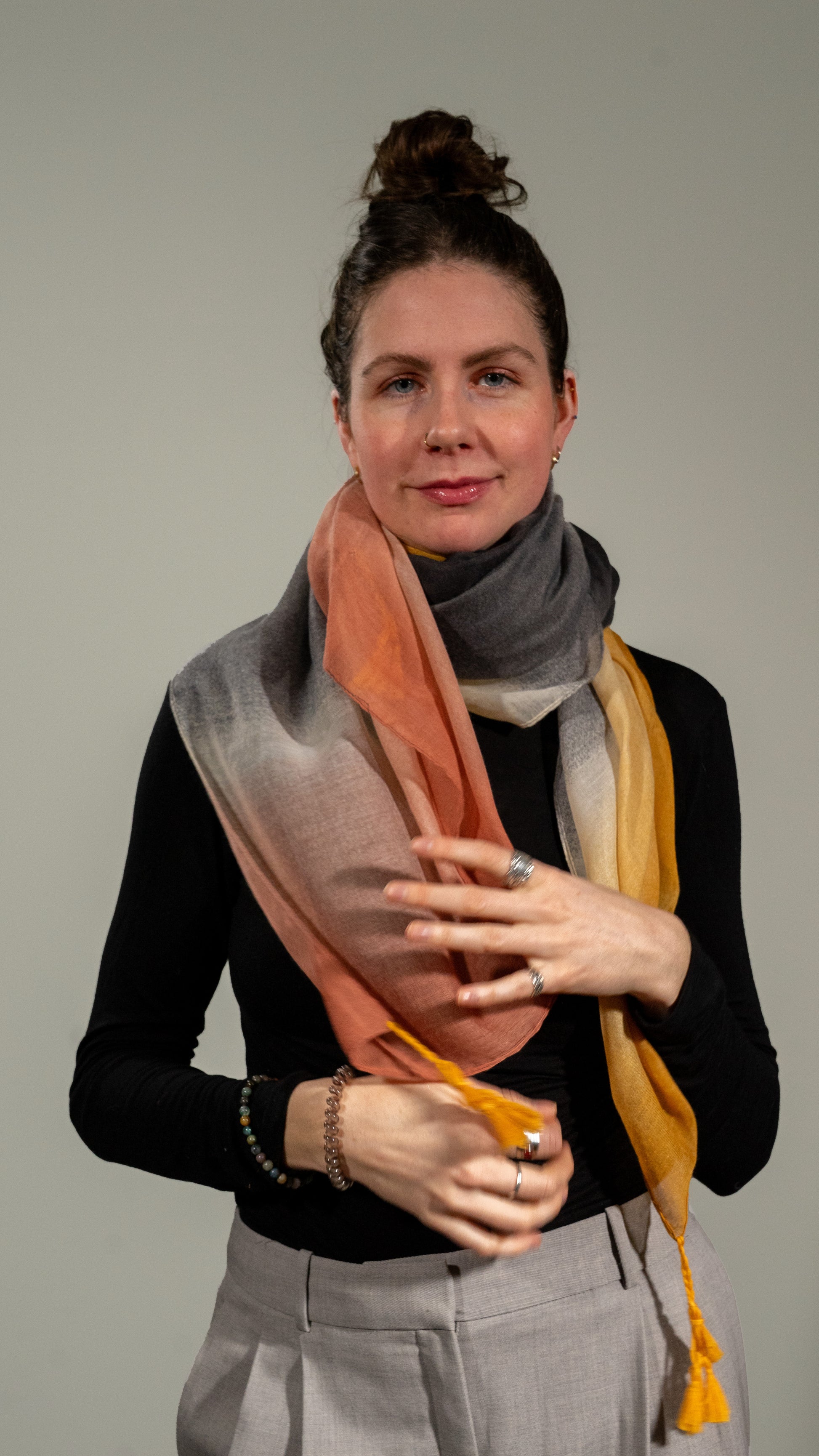 model wearing wool silk shawl with light pink/orange, yellow, white, and black. full-size shot