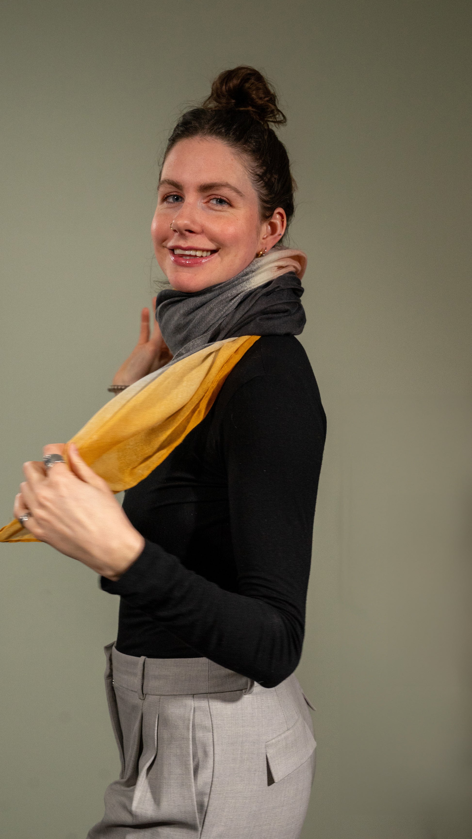 model smiling happy and wearing wool silk shawl with light pink/orange, yellow, white, and black. side
