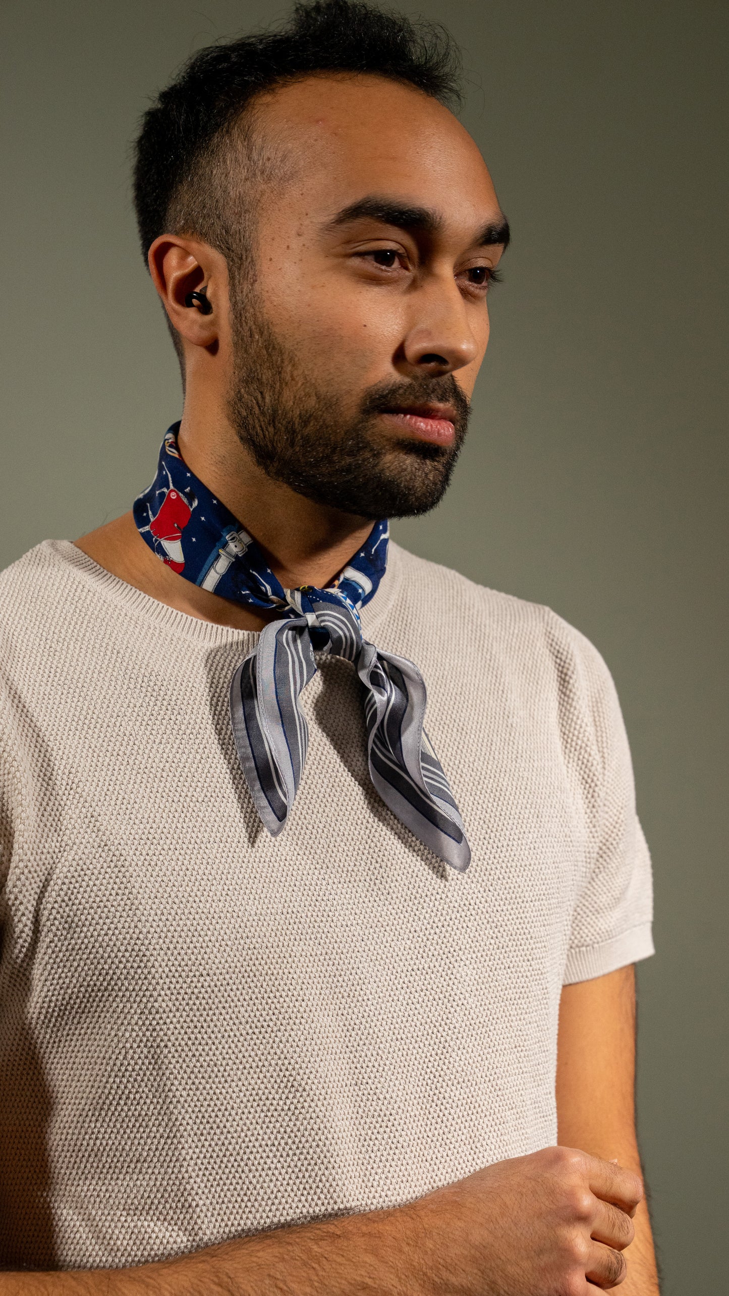 male model wearing colourful square silk scarf, 100% pure silk, design with horses and predominantly blue and white/beige tones, loosely wrapped around the neck