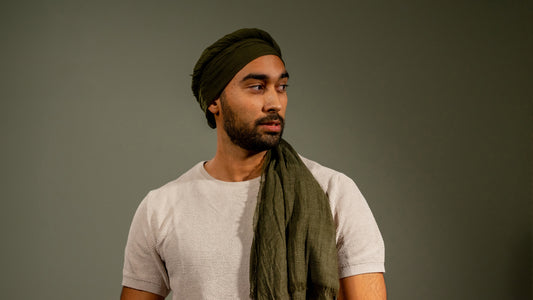 male model wearing a handwoven wool silk scarf, featuring light and dark green tones, styled as a headwrap