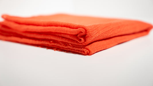 a soft, orange, handwoven wool silk scarf, gently folded over itself, forming a heart.