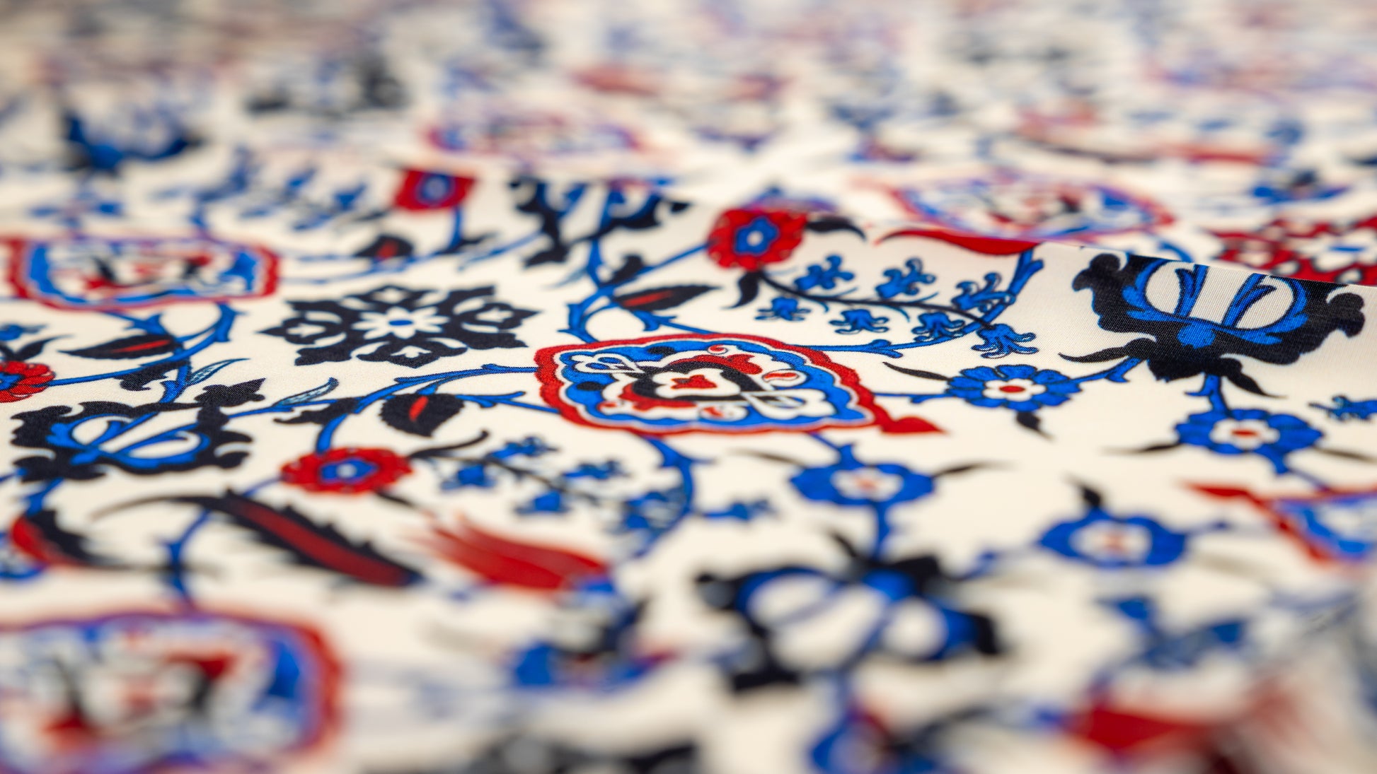 vegan silk scarf with blue, red, black and white tones, featuring intricate patterns. extreme close-up