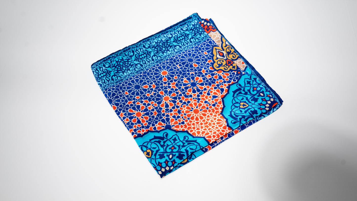 vegan silk scarf with light and dark blue, yellow, orange, and white tones, featuring intricate geometric designs. Folded