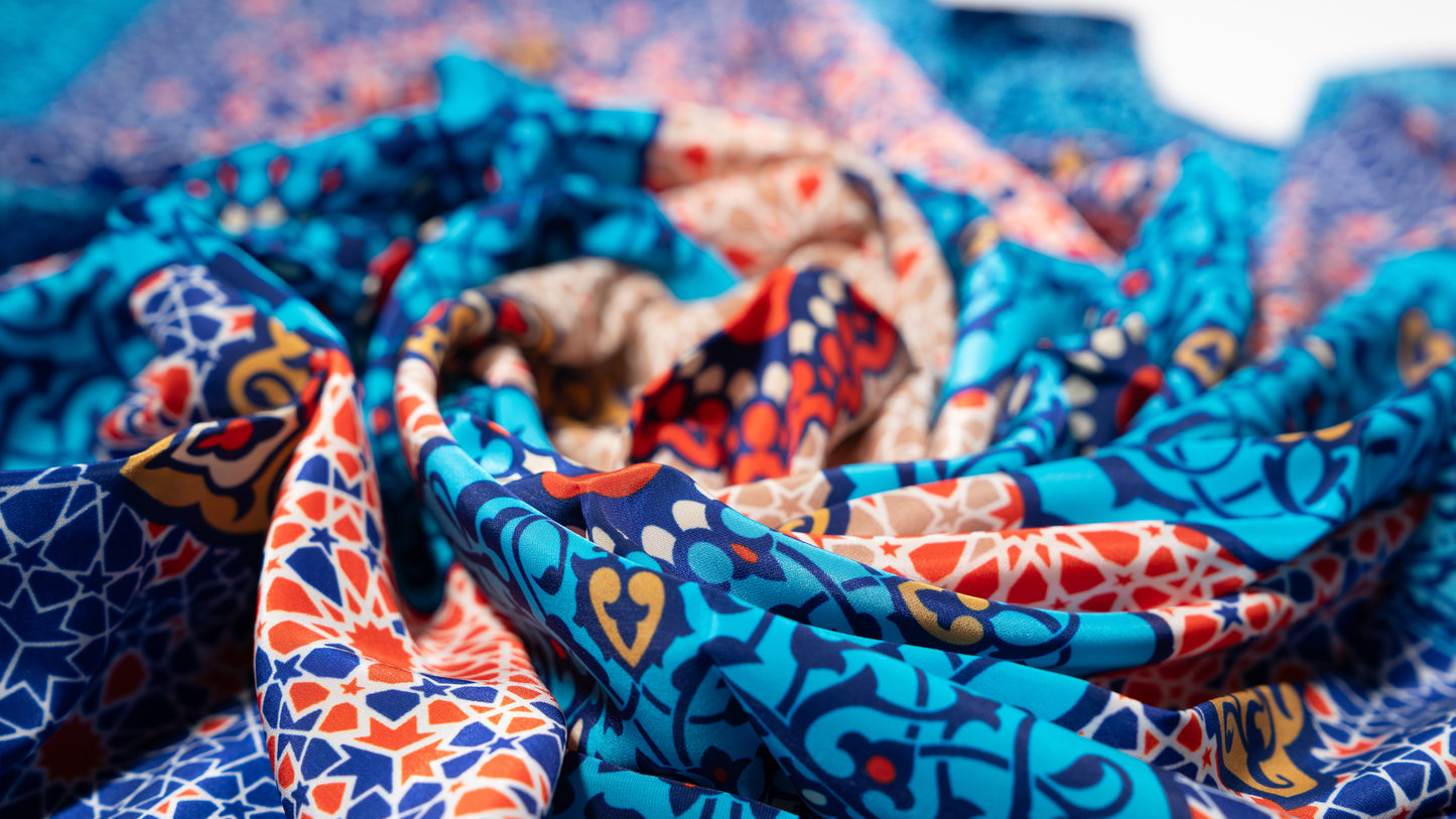 vegan silk scarf with light and dark blue, yellow, orange, and white tones, featuring intricate designs. extreme close-up