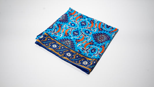 vegan silk scarf with light and dark blue, yellow, orange, and white tones, featuring intricate floral designs. Folded