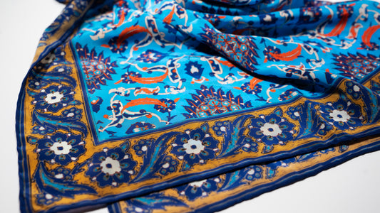 vegan silk scarf with light and dark blue, yellow, orange, and white tones, featuring intricate floral designs. close-up