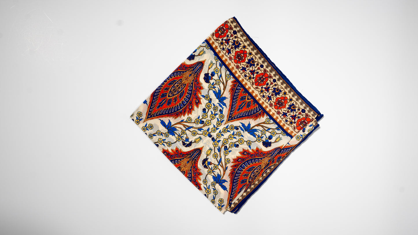 vegan silk scarf with orange, beige, blue, and yellow tones, featuring intricate floral designs. folded.