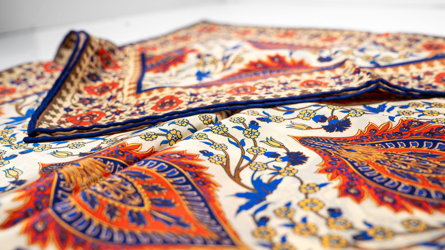 vegan silk scarf with orange, beige, blue, and yellow tones, featuring intricate floral designs. close-up