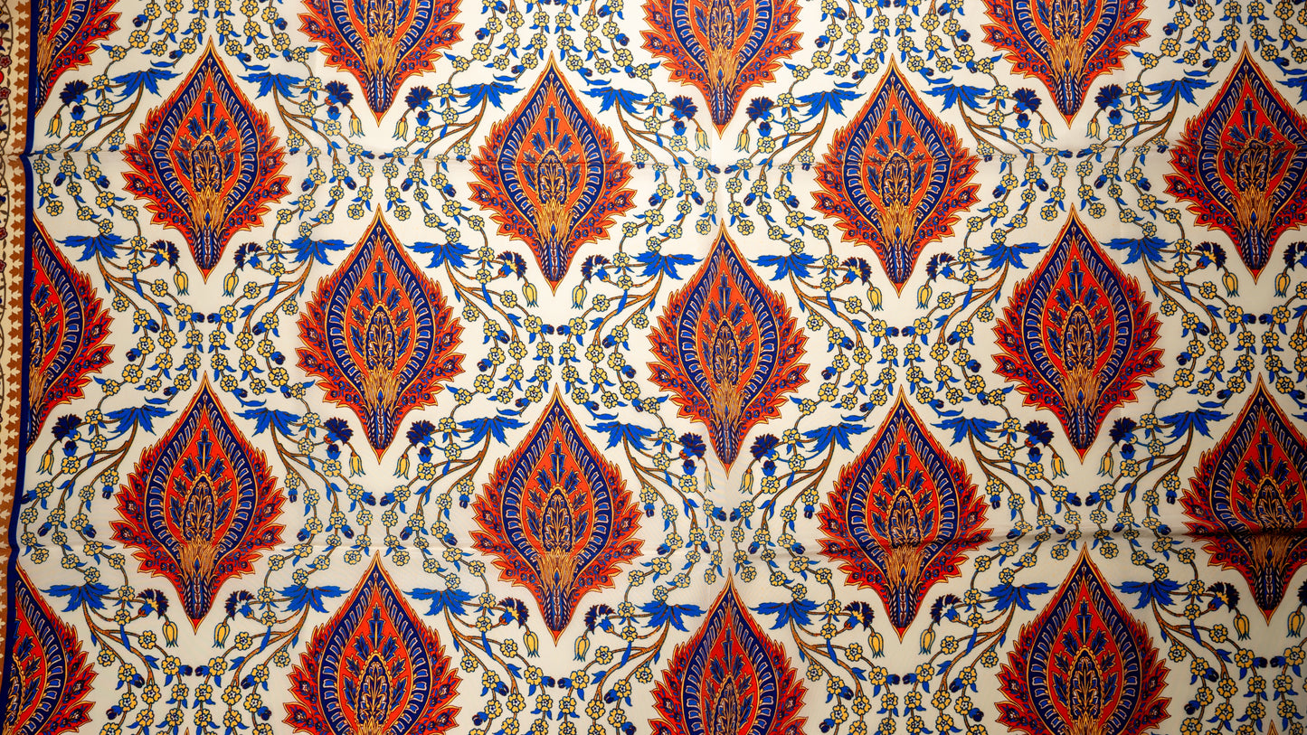 vegan silk scarf with orange, beige, blue, and yellow tones, featuring intricate floral designs. close-up on the design