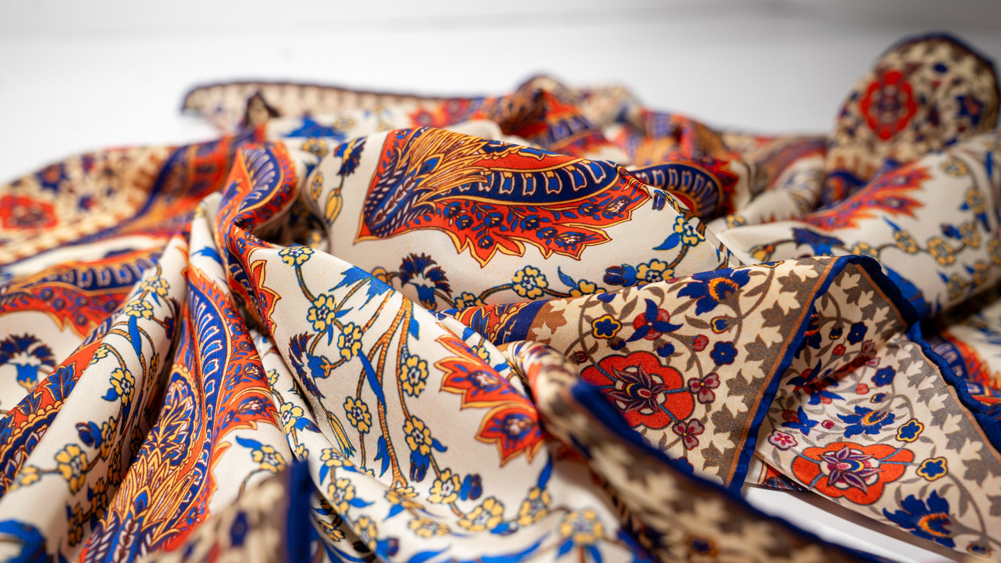 vegan silk scarf with orange, beige, blue, and yellow tones, featuring intricate floral designs. close-up on texture