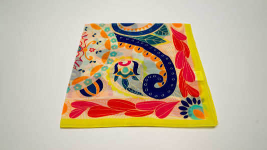 a vibrantly colourful square vegan silk scarf, predominantly yellow with intricate designs, folded.