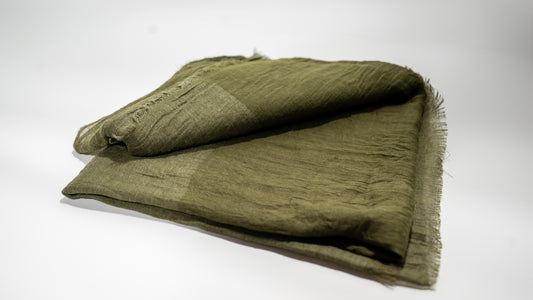 handwoven wool silk scarf, featuring light and dark green tones, gently folded over itself.