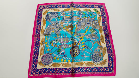 a square handwoven 100% pure silk scarf with vibrant blue, purple, and pink colours and intricate designs