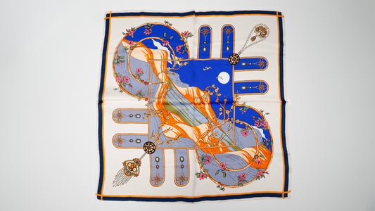 a handwoven pure silk square scarf with a brutalist and floral design, showing grey, blue, white, and orange colours.