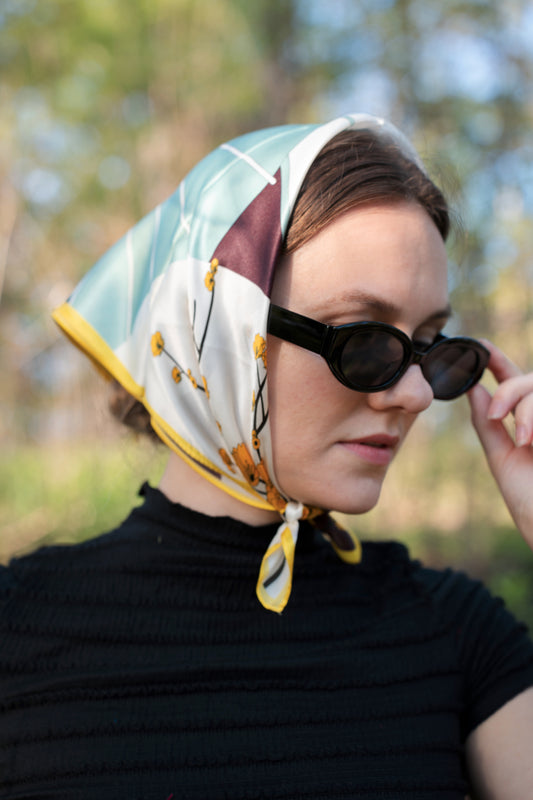 female model wearing a pure silk square scarf, "blooming yellow", as a head wrap/hair wrap.