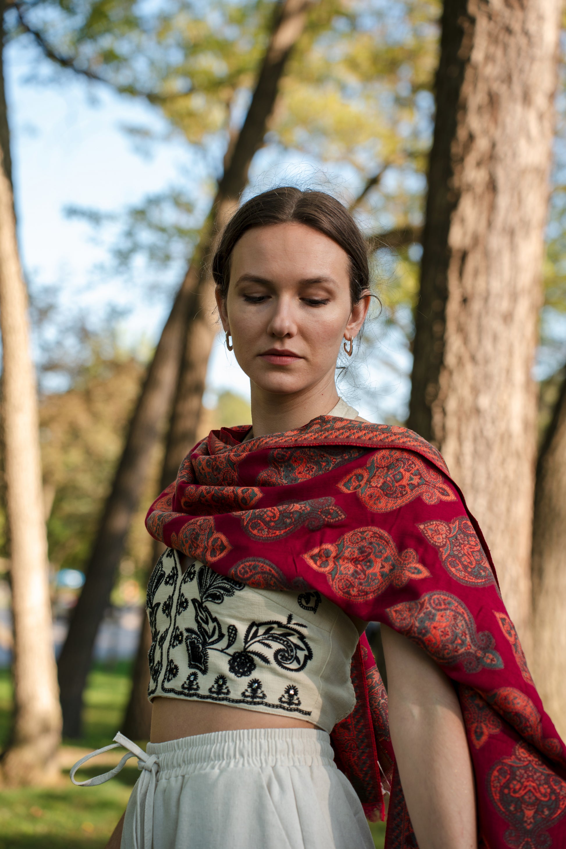 female model wearing a red cotton and wool turkish shawl, red fields.