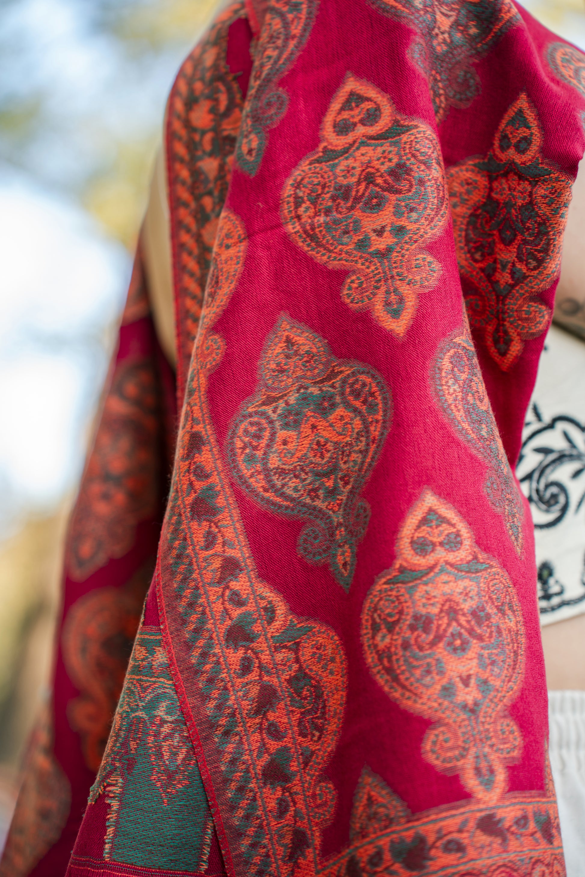 female model wearing a red cotton and wool turkish shawl, red fields. Close-up.