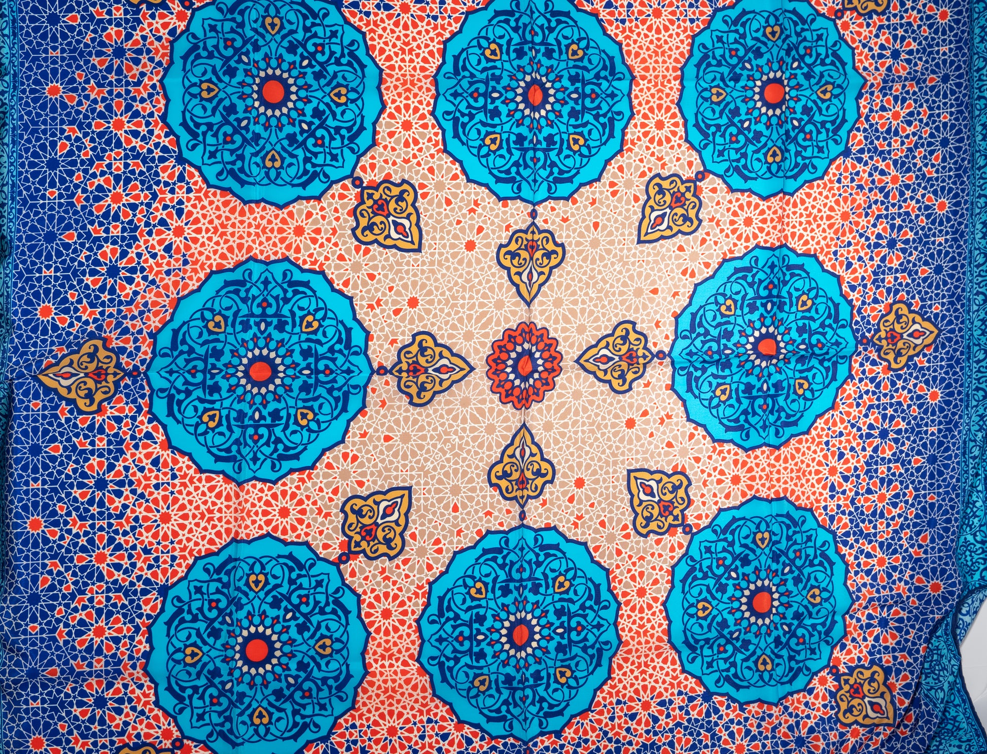 vegan silk scarf with light and dark blue, yellow, orange, and white tones, featuring intricate geometric designs. zoom on designs